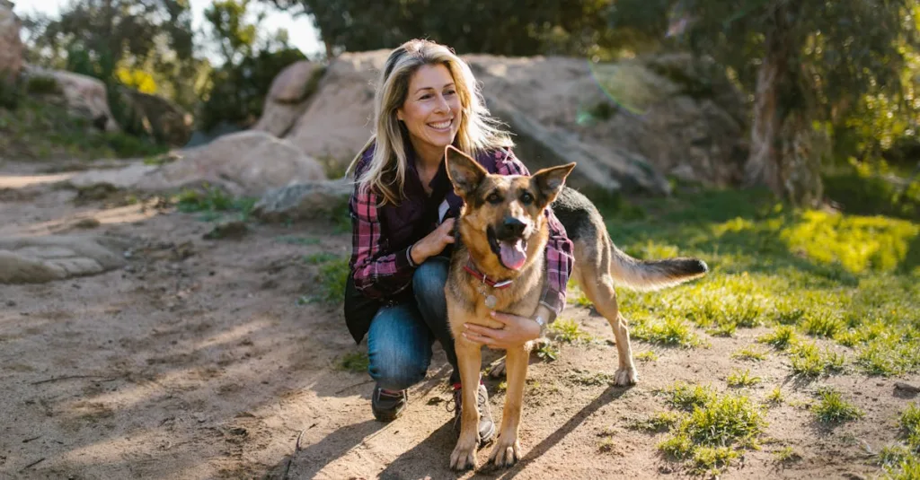 A cheerful woman hiking with her German Shepherd on a sunny day in nature.